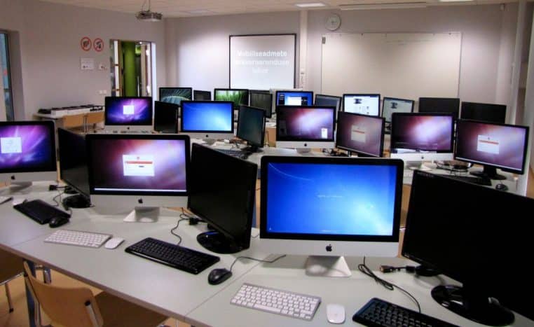 Salle informatique remplie d’iMac et d’écrans, dédiée au développement d’applications et aux tests logiciels.