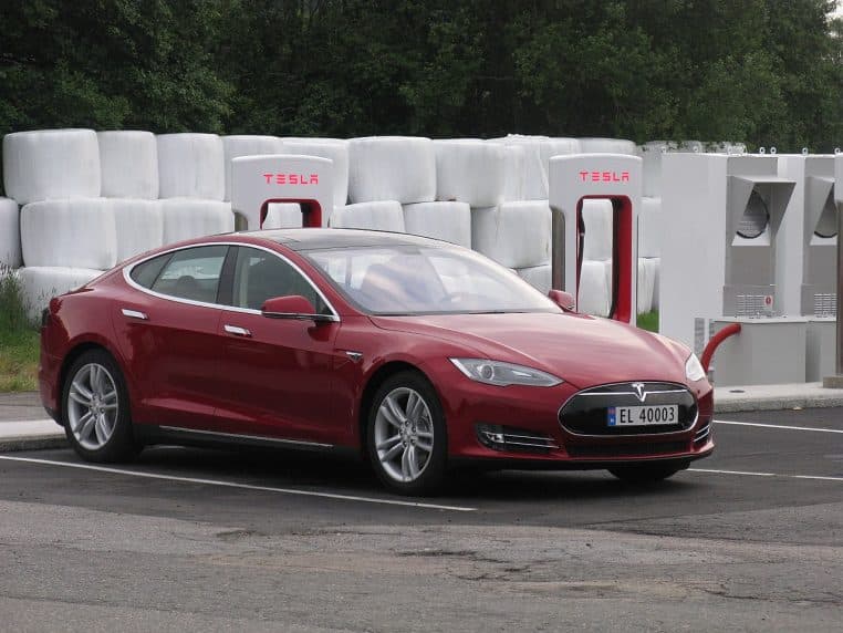 Tesla rouge connectée à une borne de recharge rapide