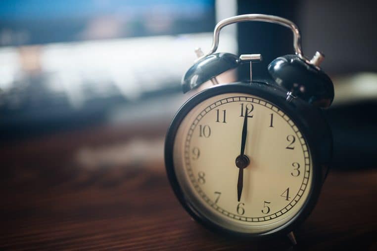 Réveil mécanique chromé posé sur une surface claire, cadran lisible avec aiguilles noires, composition horizontale.