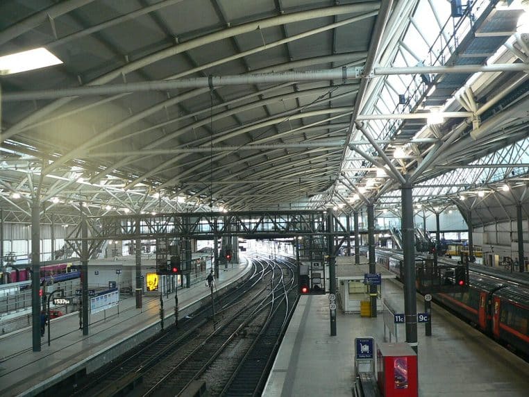 Vue d’ensemble d’une partie traversante de la gare de Leeds, avec toitures et aiguillages visibles depuis une passerelle en hauteur.