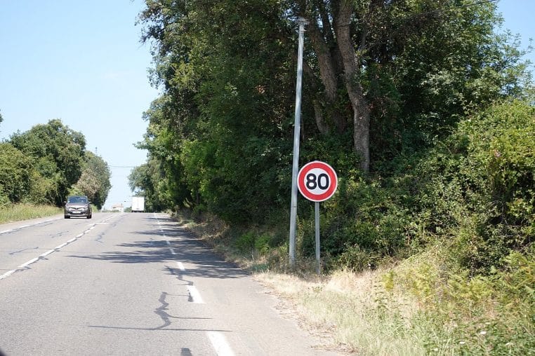Panneau circulaire rouge et blanc indiquant 80 km/h sur une route française, environnement végétalisé