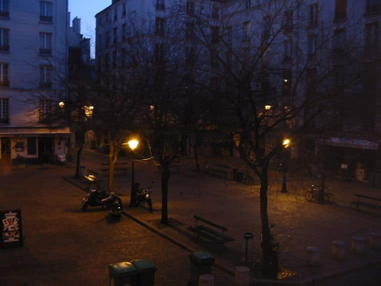 Place parisienne illuminée de nuit, terrasses et réverbères