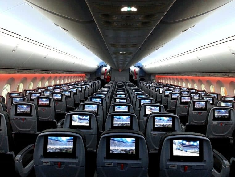 Cabine de Boeing 787 avec sièges gris et écrans, rangées visibles jusqu’au fond, configuration large.