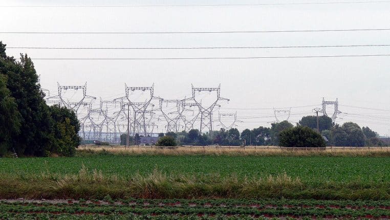 Paysage côtier avec faisceaux de lignes haute tension, prairies au premier plan près de la centrale de Gravelines.