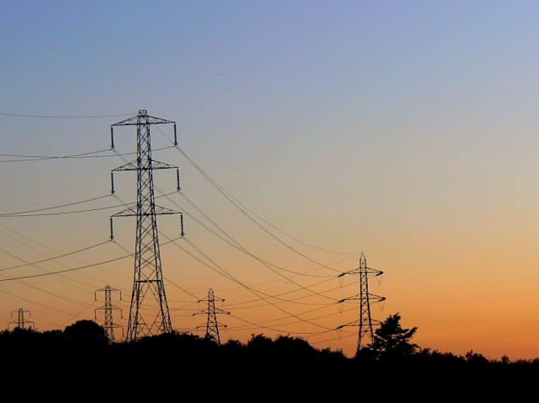Pylônes à l’horizon sous un ciel orangé.