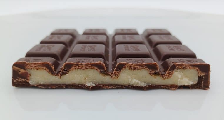 Tablette de chocolat noir sectionnée, garnie de pâte d’amande, évocation d’une pause sucrée et réconfortante.