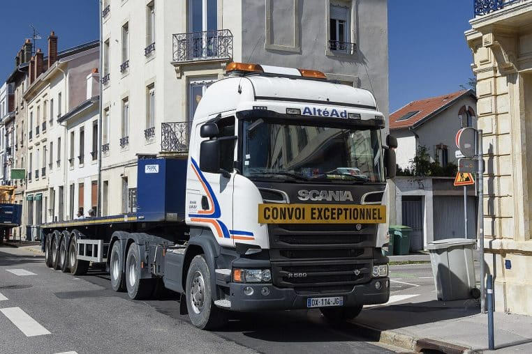 Rue de ville avec camion et immeubles, chantier d’une résidence étudiante.