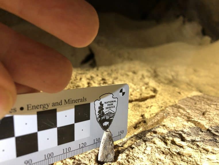 Dent de requin affleurant dans une paroi, mesurée sur une réglette, environnement calcaire jaune clair de la grotte.