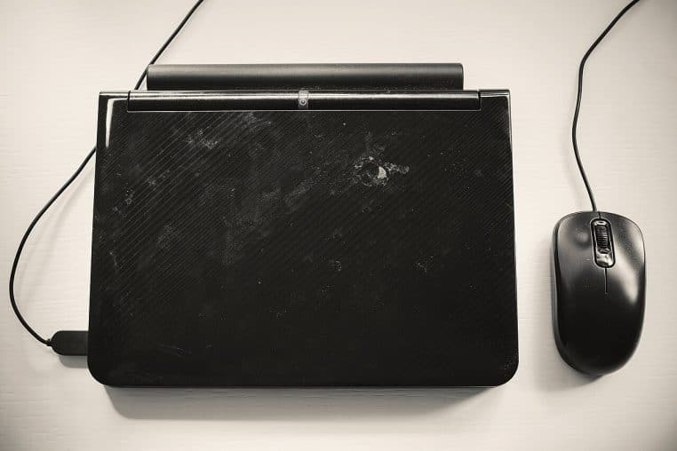 Petit ordinateur portable sur table blanche, photo épurée figurant la simplicité d’un PC prêt à l’emploi.