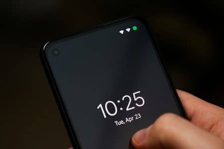 Gros plan sur un smartphone montrant un petit point vert dans la barre d’état