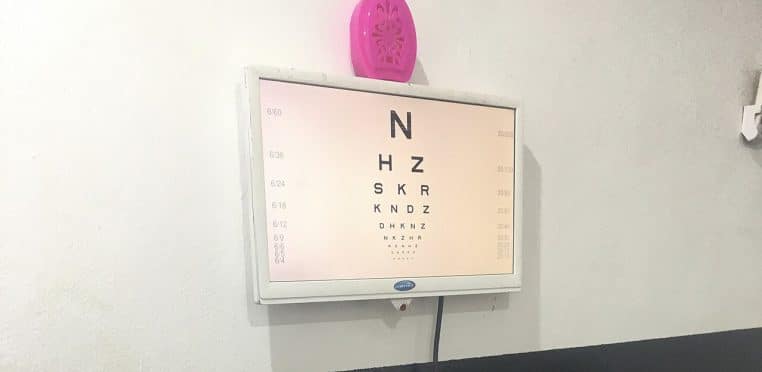 Tableau de lecture de type Snellen affiché en clinique, utilisé pour tester l’acuité visuelle lors des visites médicales.