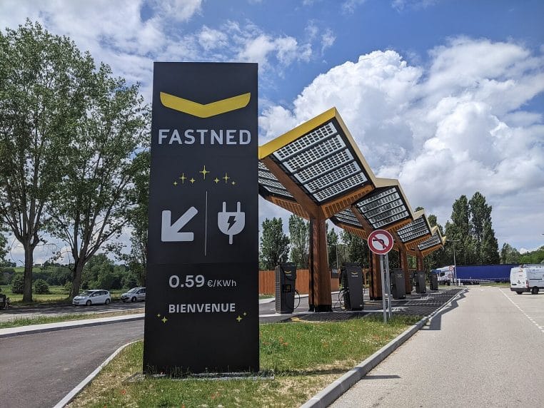 Station Fastned sur l’aire de Romagnieu, autoroute A43 ; auvent jaune caractéristique, bornes rapides actives.