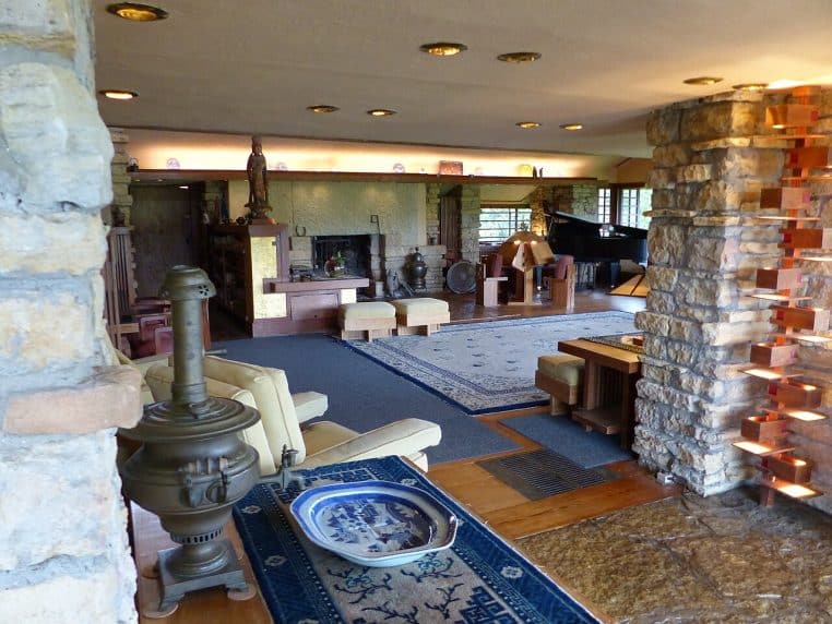 Grand salon moderniste avec murs en pierre, canapés et lampes d’appoint diffusant une lumière chaude.