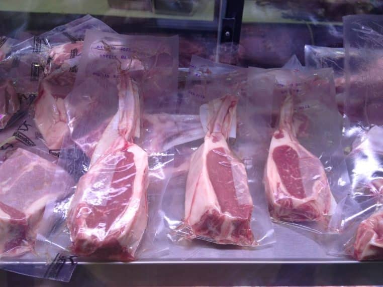 Viandes crues emballées sous vide alignées dans une vitrine réfrigérée, prêtes à la vente.