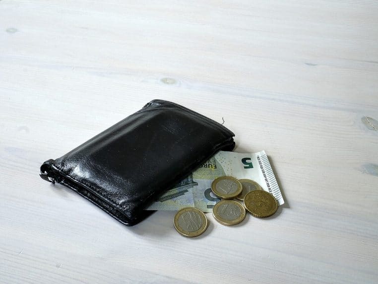 Portefeuille en cuir posé sur une table avec billets et pièces, ambiance domestique, évoquant la gestion d’un foyer.