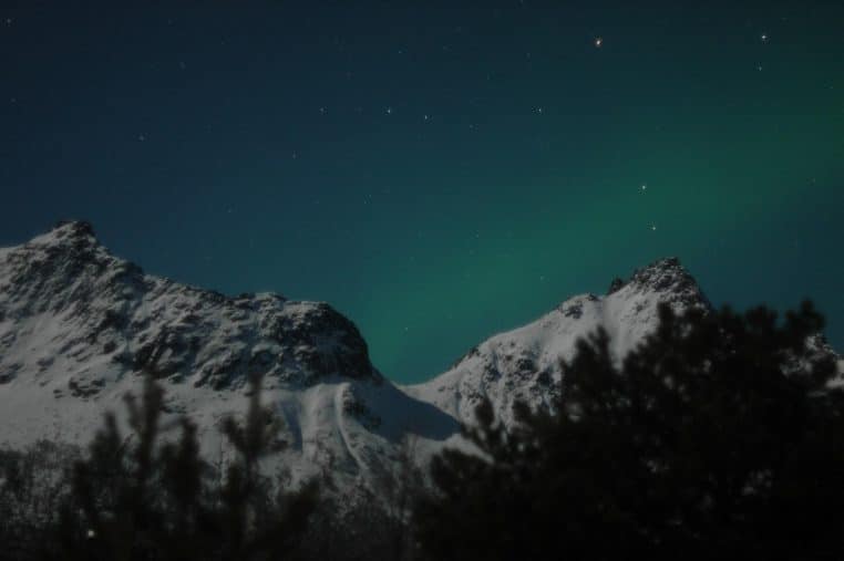 Aurores vertes sur relief enneigé, nuit claire.