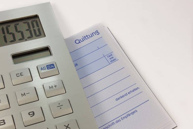 Calculatrice posée sur des factures et un reçu, symbolisant le règlement des dépenses