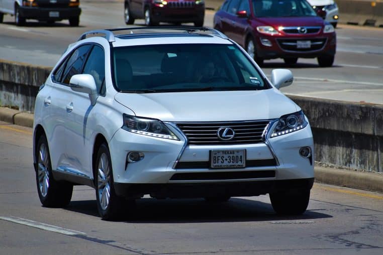 Conductrice tenant un smartphone en conduisant, trafic urbain à l’arrière-plan.