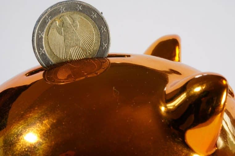 Tirelire rose à côté de pièces en euro empilées.