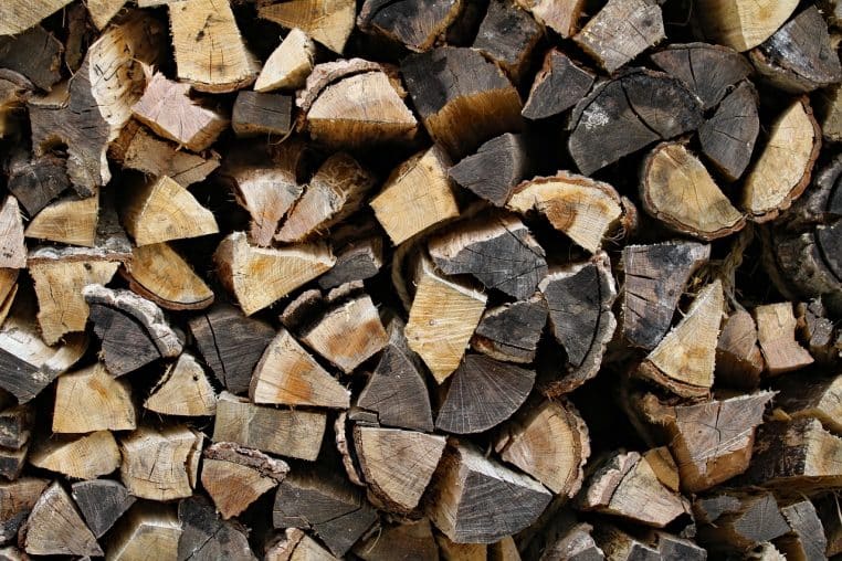 Bûches fendues et hache posée devant un abri bois