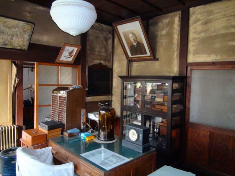 Cabinet de consultation médical traditionnel, bureau et table d’examen, éclairage naturel sur la pièce.