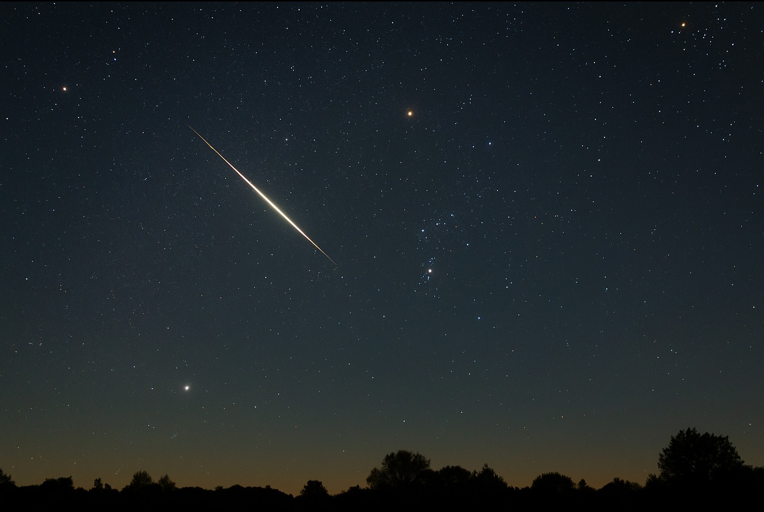 Ciel nocturne avec la constellation d’Orion et une étoile filante des Orionides traçant un sillage lumineux au-dessus d’un horizon d’arbres.