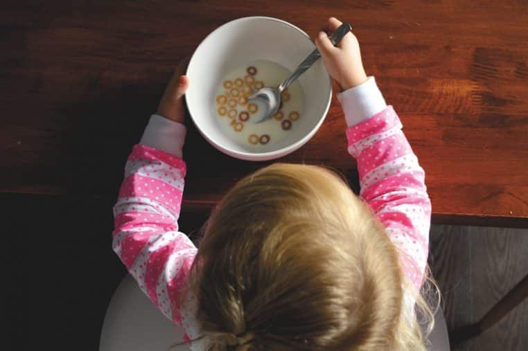 Enfant mangeant des céréales dans la cuisine, ambiance matin d’école.