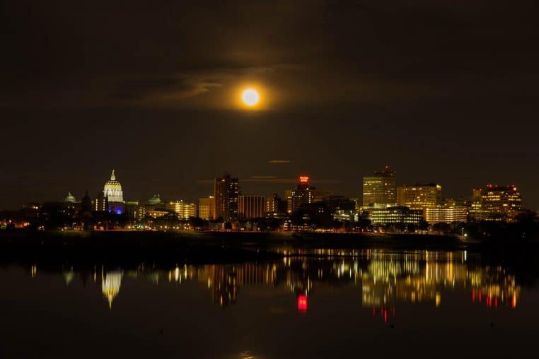 Super Lune se levant derrière une skyline au bord de l’eau
