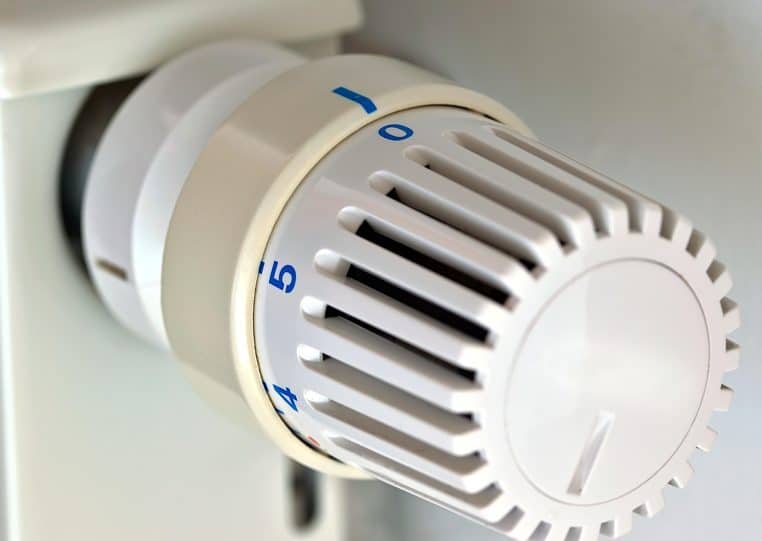 Gros plan d’une tête thermostatique réglée pour l’hiver sur un radiateur blanc