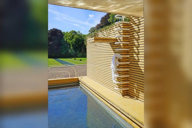 Bassin rectangulaire turquoise devant une villa en briques jaunes