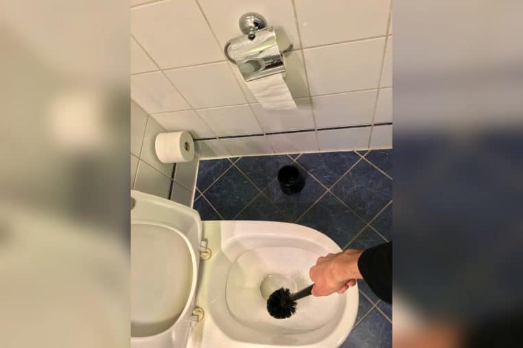 Salle de bains d’hôtel en Norvège, brosse de WC posée près de la cuvette.