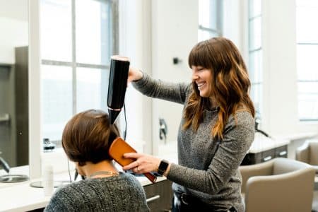 Coiffeuse sèche les cheveux d'une femme