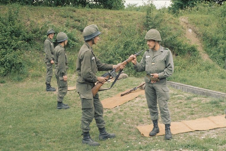Des soldats français en treillis vert contrôlent leurs fusils sur un pas de tir herbeux lors d’un exercice d’instruction au tir.