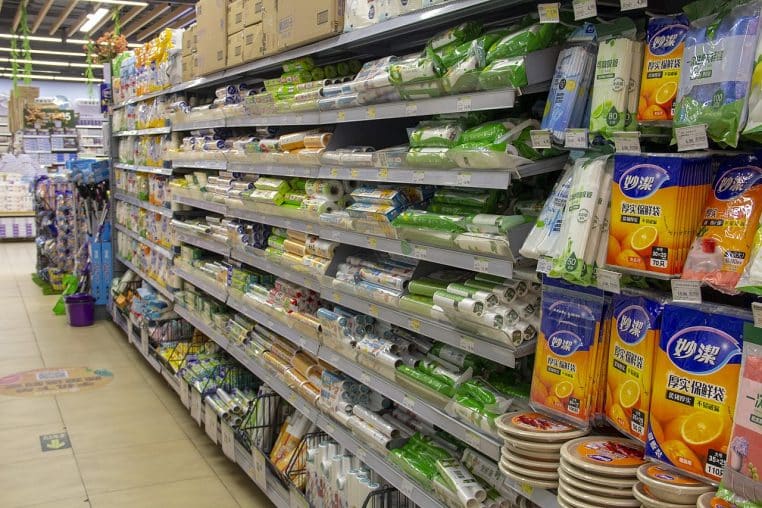 Rouleaux de film étirable alignés sur une étagère de magasin, vue de face en rayonnage, emballages visibles et texture du plastique