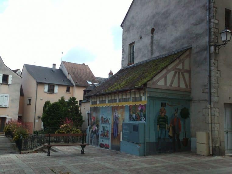 Devanture d’une boutique de fleurs à Montargis, étalage coloré de bouquets et plantes en pots sous auvent, prise en plan large, orientation horizontale.