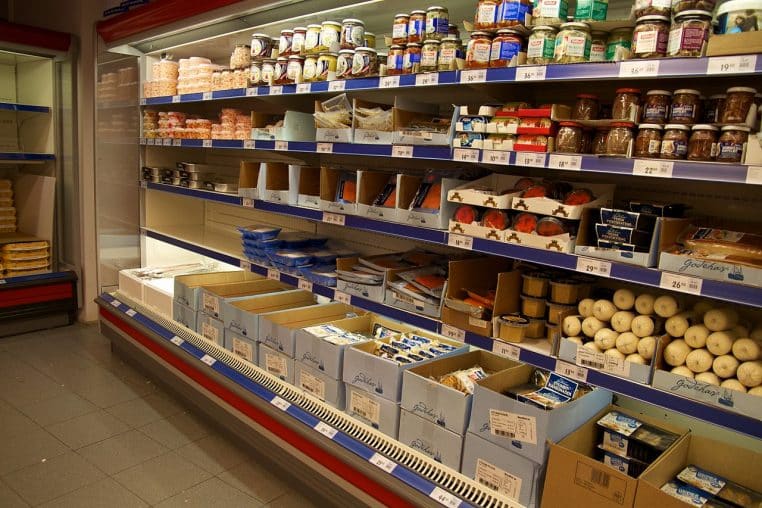 Long comptoir réfrigéré vu de face dans une enseigne Rema 1000, présentant des produits frais et surgelés.