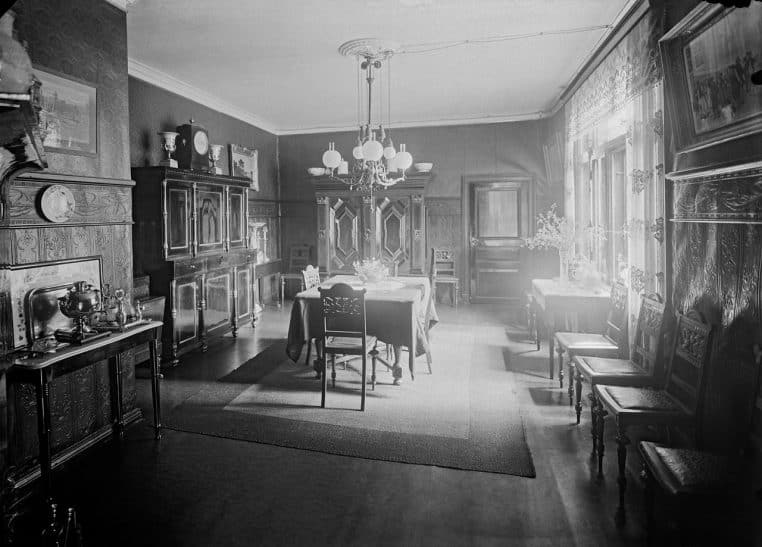 Salle à manger finlandaise ancienne, grande table en bois et mobilier épuré, lumière naturelle soulignant une atmosphère familiale et sereine.