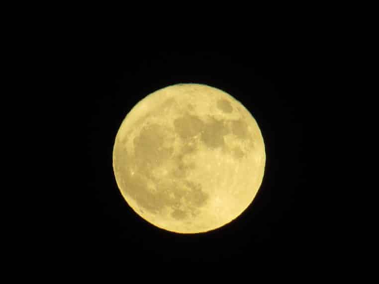 Superlune cadrée au-dessus des toits à Albufeira, ciel sombre, image large et nette en orientation paysage.