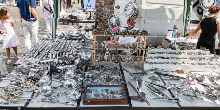 Vue générale d’un marché de pièces détachées pour voitures anciennes, avec plusieurs véhicules de collection alignés en arrière-plan.