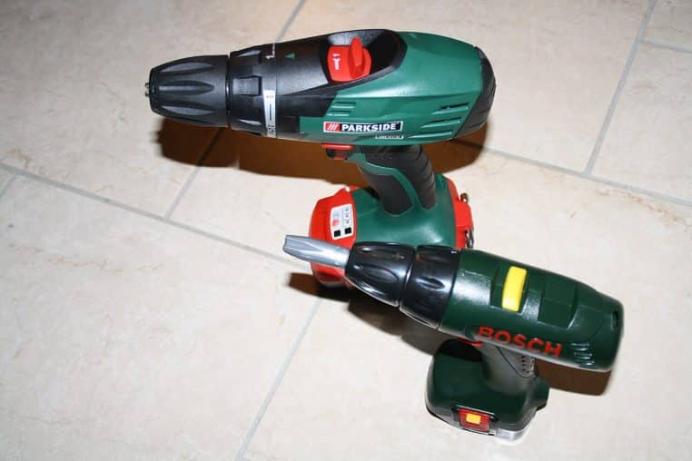 Deux perceuses Bosch vertes posées sur plan de travail en atelier, éclairage naturel, format horizontal.