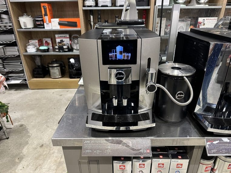 Machine à café haut de gamme exposée en magasin, avec de nombreux réglages visibles sur la façade.