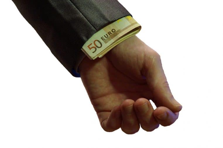 Billets en euros dissimulés dans la manche d’un costume, suggérant un don ou un transfert d’argent difficile à tracer.