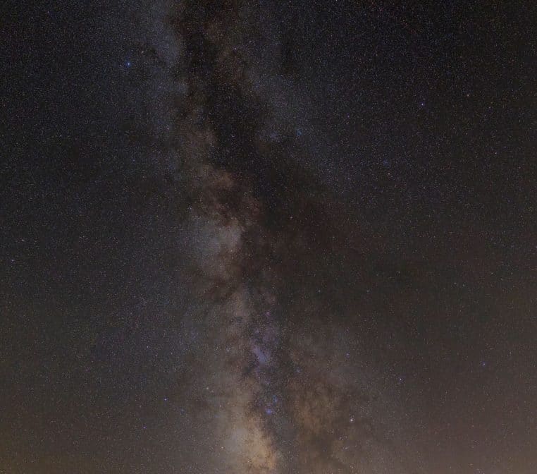 Bande verticale lumineuse de la Voie lactée se détachant dans un ciel noir parsemé d’innombrables étoiles en haute résolution.