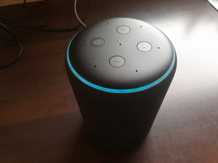 Enceinte Amazon Echo en fonctionnement avec anneau lumineux bleu, symbole d’un assistant vocal prêt à écouter des commandes
