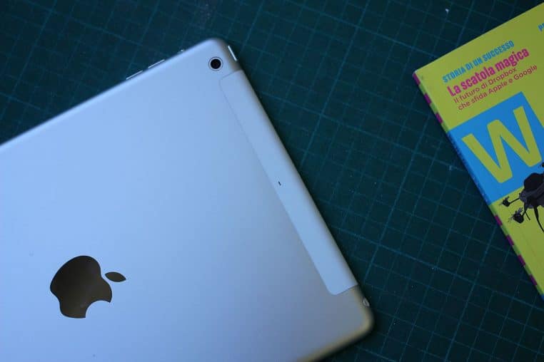 Gros plan sur un iPad Air posé à plat sur une table avec son écran allumé, photographié dans une boutique d’électronique très lumineuse.