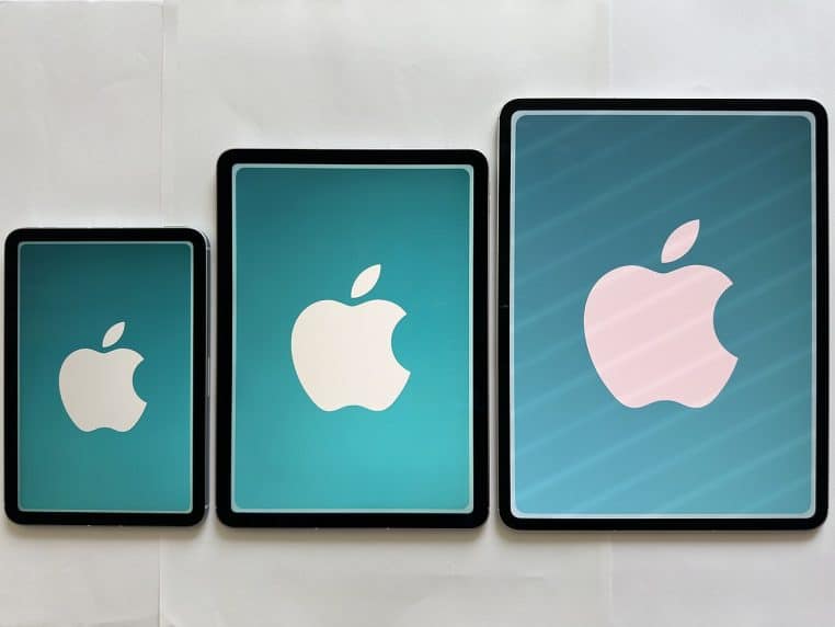 Alignement de plusieurs iPad de générations différentes sur un présentoir, vus de dessus, dans un environnement de magasin moderne.