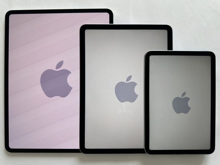 Rayon d’exposition avec plusieurs modèles d’iPad alignés sur une table en bois claire dans un Apple Store très éclairé, vus de trois quarts.