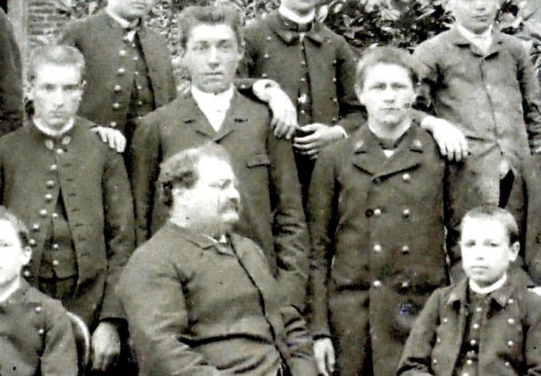 Élèves et professeur du collège d’Auxerre en 1890 : portrait de groupe en extérieur, visages cadrés de près.