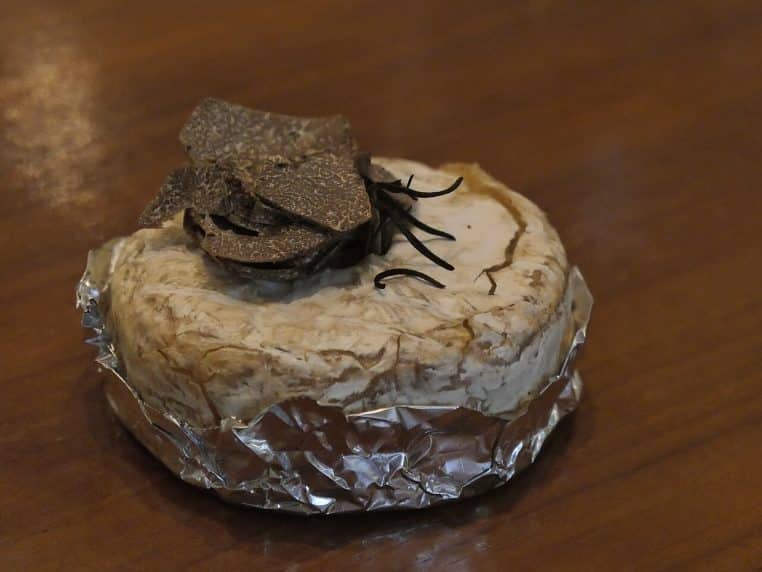 Camembert rôti entaillé, fromage coulant au centre, tranches de truffe posées sur la croûte encore chaude