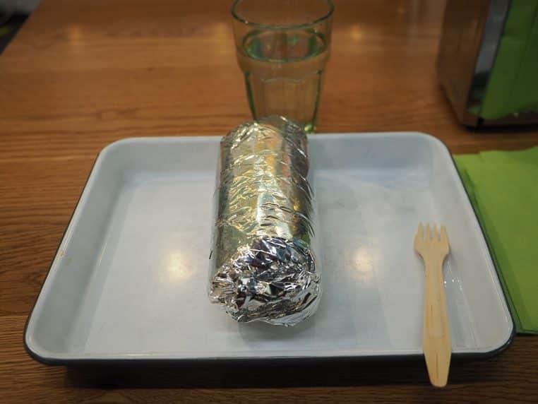 Burrito entièrement enveloppé dans une feuille d’aluminium, posé sur un plateau, scène de restauration en intérieur